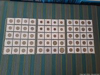 Three 20-pocket album pages holding 60 flipped coins