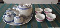 Full set on display: teapot, serving plate, four blue cups inverted, four pink cups upright