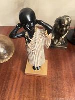 Front view of resin figurine on base showing beaded garment and necklace details