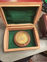 compass inside open wooden box showing green felt lining