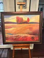 Frontal view of framed autumn landscape painting on easel