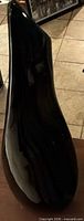 side view of tall glossy black glass vase on small table