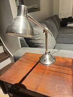Side view of brushed nickel adjustable desk lamp on wooden table