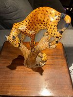 Full view of leopard sculpture on branch from front angle