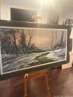 Full view of framed oil landscape painting on easel