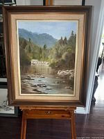 Front view of framed river landscape painting on easel