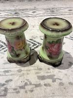 Front view of both green porcelain candlesticks showing floral panels and overall shape
