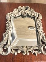Front view of ornate Rococo mirror on wooden surface