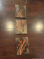 Three stacked floral abstract canvas panels on floor