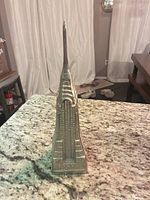 Full left side view of silver metal Chrysler Building replica