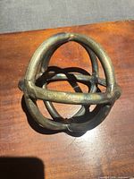 Top view of welded metal orb showing intersecting bands and patina