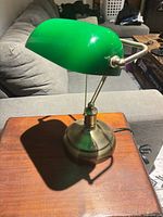 Full view of lamp on table showing green glass shade, brass-tone base, pull chain