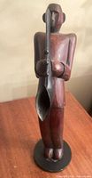 front view of carved wood saxophonist with metal instrument on base