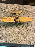 Top frontal view showing overall yellow biplane design, dual wings, propeller and landing gear