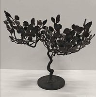 Full view of sculptural candle holder showing two branch arms and round base