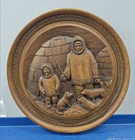 Full view of round carved plaque showing Inuit scene