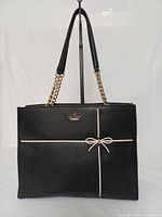 Front view of black Kate Spade Cherry Street Phoebe satchel showing bow trim and chain straps
