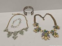 All four jewelry pieces laid out: two necklaces, silver cuff, silver link bracelet