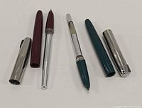 Two disassembled HERO fountain pens showing barrels, caps and nib sections