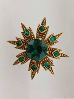 Front view showing starburst brooch pendant with central and surrounding emerald-green rhinestones
