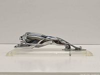 Right side profile of chrome lion hood ornament on acrylic base