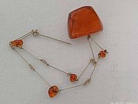 Front view of brooch showing large amber cabochon, chain and small amber nuggets