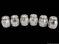 Front view of six hammered sterling silver shakers in a row