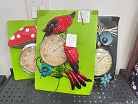 Front view of three packaged metal wall thermometers: mushroom, cardinal, owl