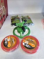 Full lot showing two garden staple packs, rotary sprinkler, two trimmer line spools
