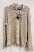 Front view of beige ribbed knit sweater hanging, shows overall design