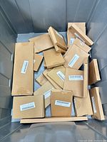 Top view of grey tote holding multiple sealed brown boxes with barcodes