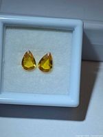 Pair of pear-cut golden yellow sapphires in display box