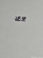 Pair of square colorless spinel gemstones on neutral background