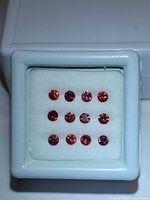 Front view of 12 round rubies arranged in box