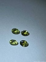 Four oval mint green sapphires on neutral background