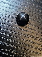 Top view of round black star diopside showing four-ray star
