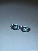 Two oval blue aquamarines laid on neutral surface