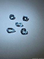 Five faceted blue aquamarine stones grouped on white background