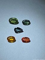 All five multicolour faceted sapphires arranged on white background