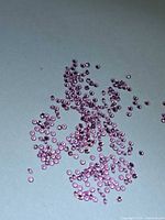Scatter of small round pink sapphires on light background