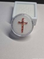 Round gem case holding cross-arranged princess-cut pink-orange sapphires