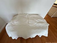 Coverlet folded on surface with two shams displayed