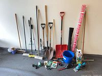 Group of long-handle tools, buckets, pots and small tools against wall