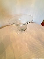 Full view of glass trumpet vase on plexiglass stand