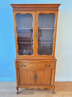 Front view of maple china cabinet showing glass doors, lower drawer, cabinet doors and hardware
