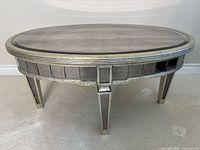 Front view of oval mirrored coffee table, showing mirrored panels and legs