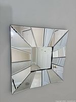 Front view of square sunburst wall mirror mounted on wall