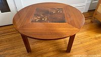 Full view of round teak coffee table showing tile inset and overall form