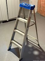 Full view of 4-foot aluminum step ladder standing unfolded