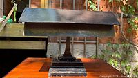 Front view of black metal Art Deco desk lamp on wooden surface